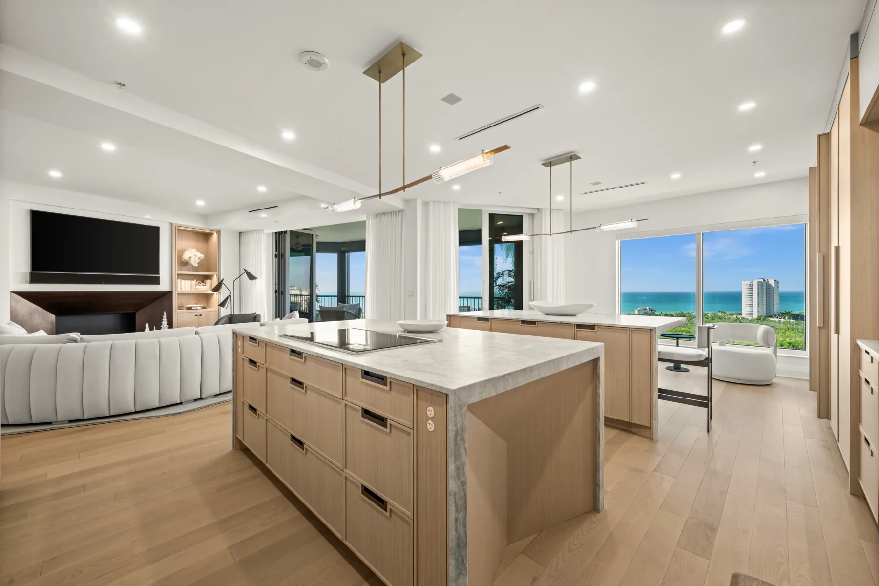 Renovated Naples high-rise kitchen with oak cabinetry, marble island, and Gulf view
